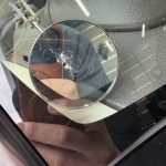 フロントガラスの飛び石の打痕から伸びたヒビを点検ミラーで確認している修理前の状態