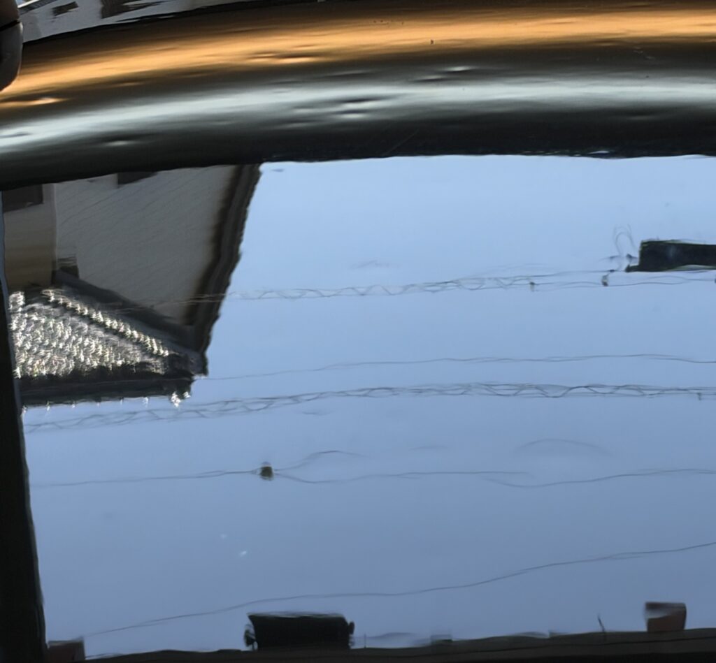 ボルボ240の屋根の雹害。ライトと空の映り込みが波打っている修理前の状態